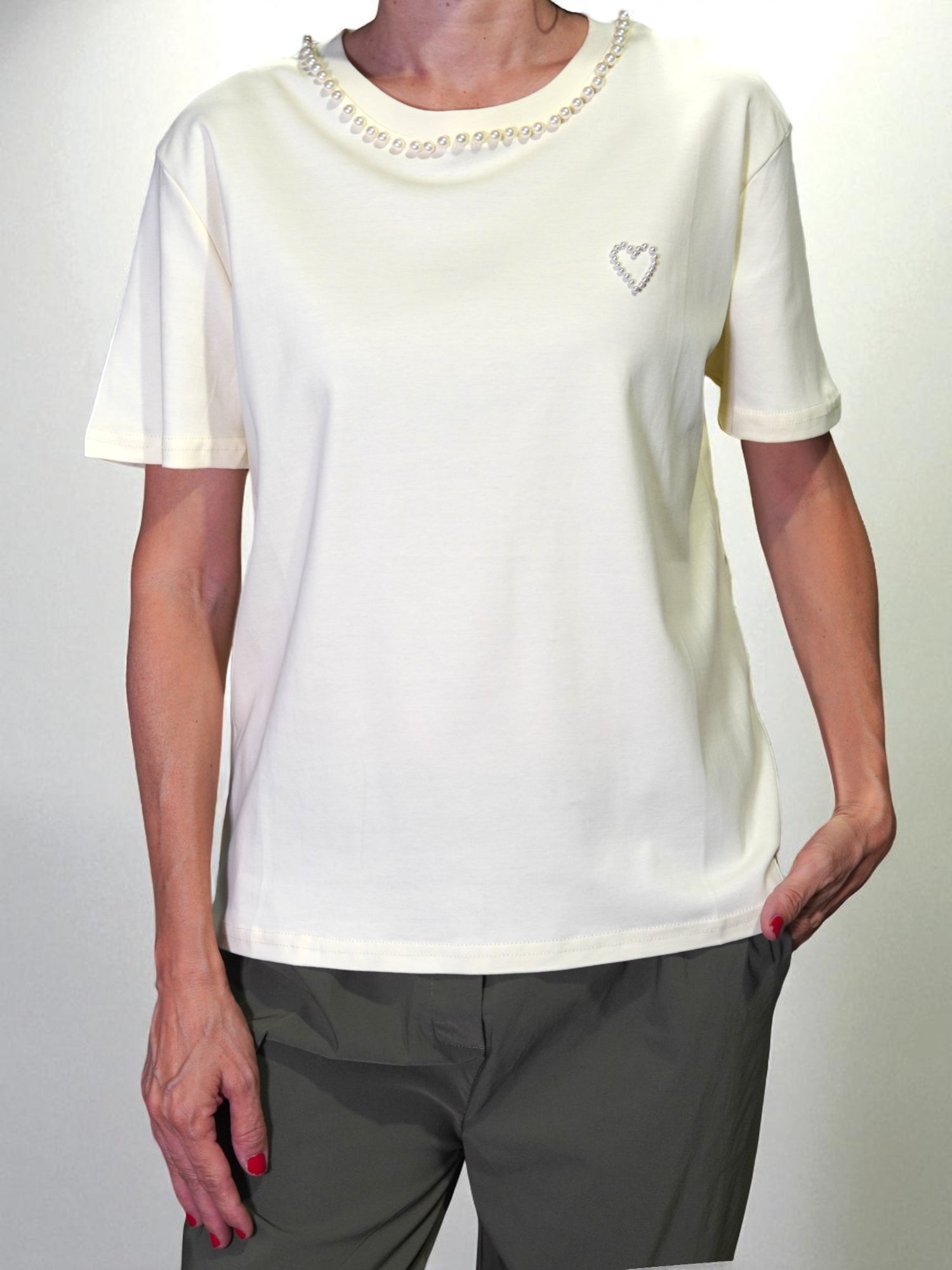 Tricou crem purtat de model, cu perle aplicate la guler și inimioară decorativă