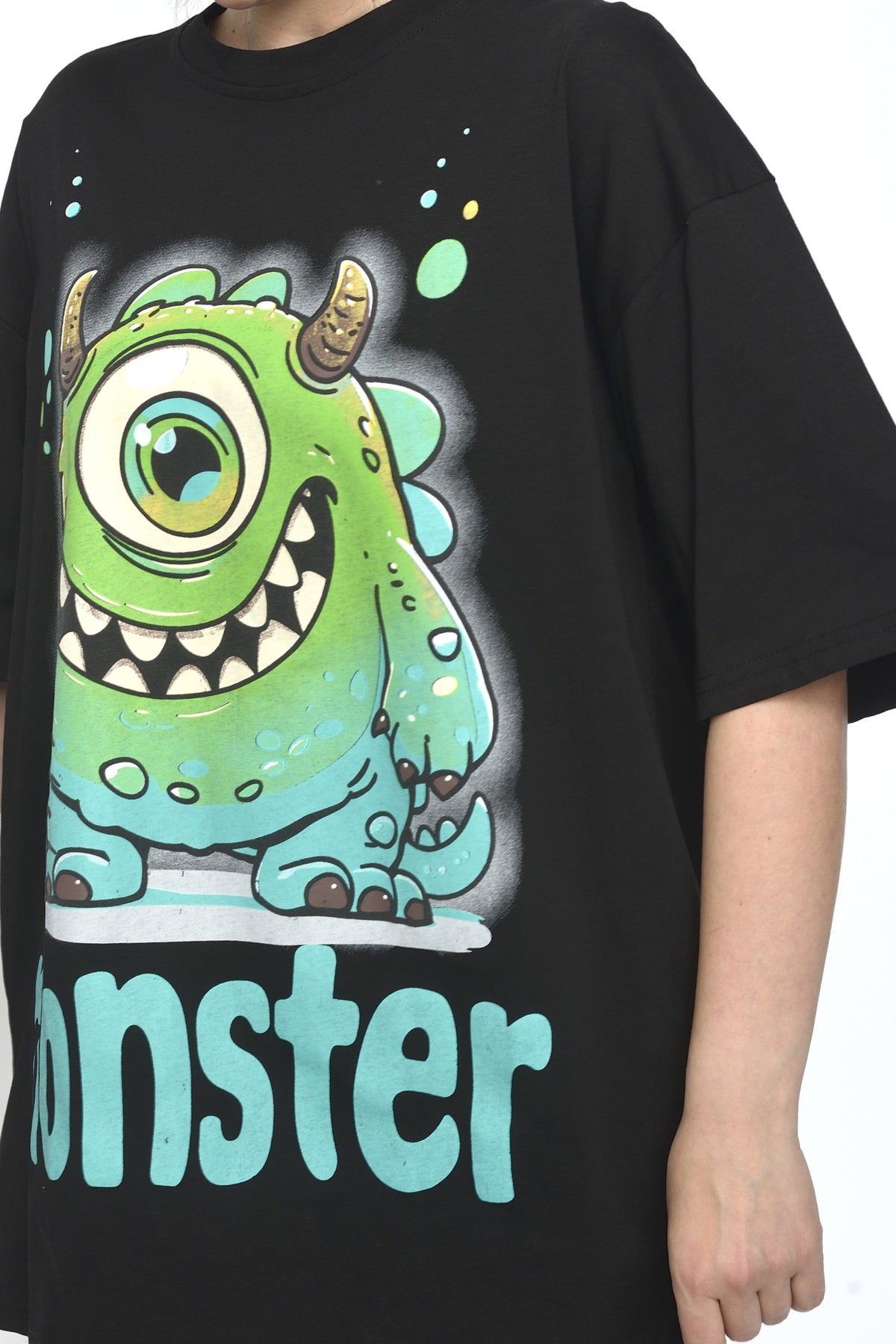 Detaliu imprimeu cu monstru verde și text „monster” pe tricou oversize