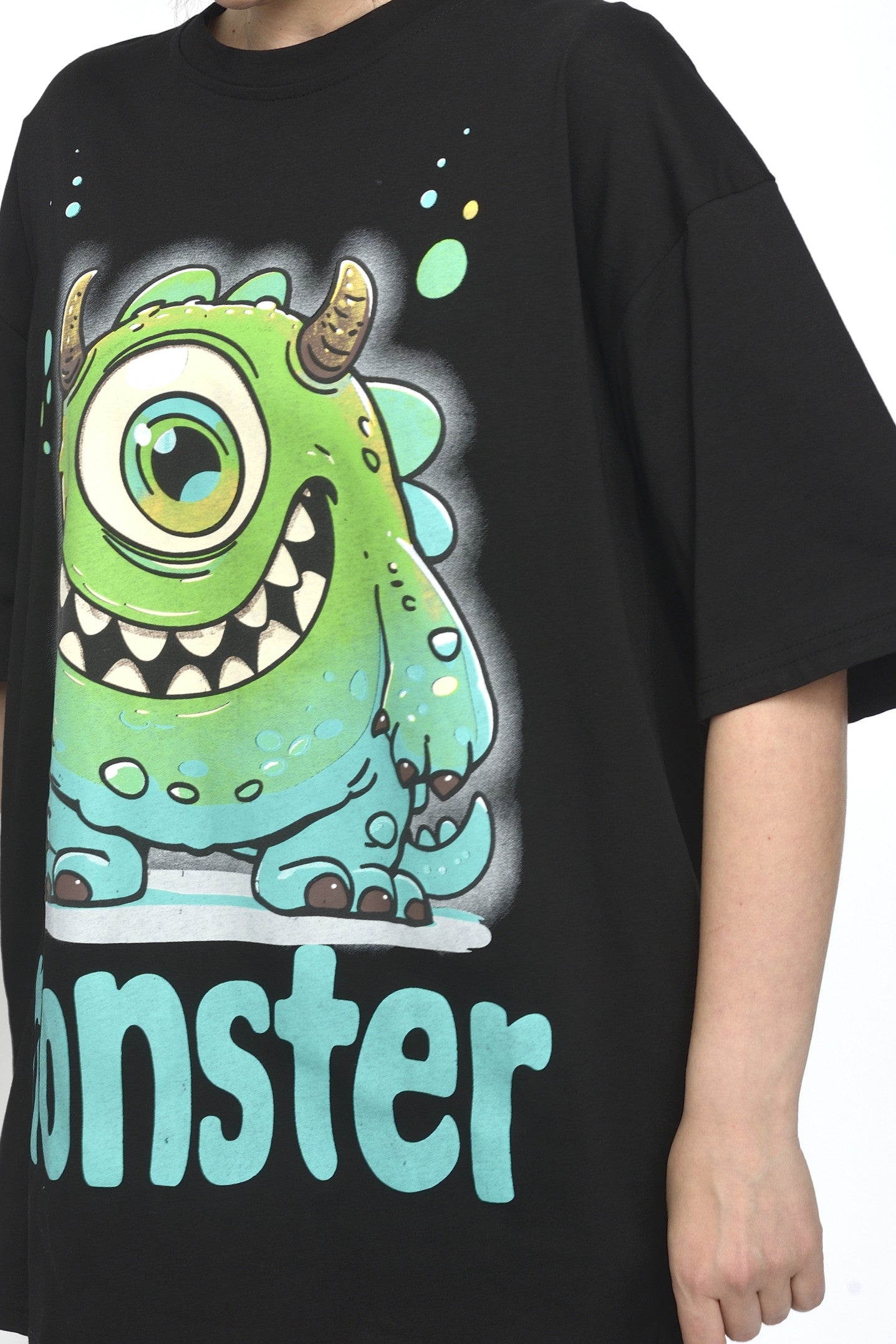 Detaliu imprimeu cu monstru verde și text „monster” pe tricou oversize
