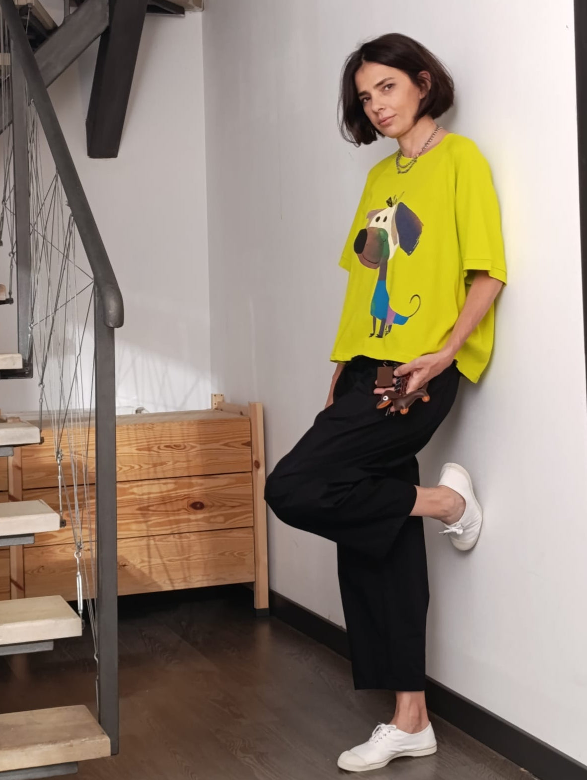 Femeie poartă tricou galben cu cățel desenat și pantaloni largi negri casual