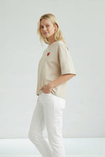Ținută completă cu tricou oversize bej și pantaloni deschiși, accent pe croiala amplă.