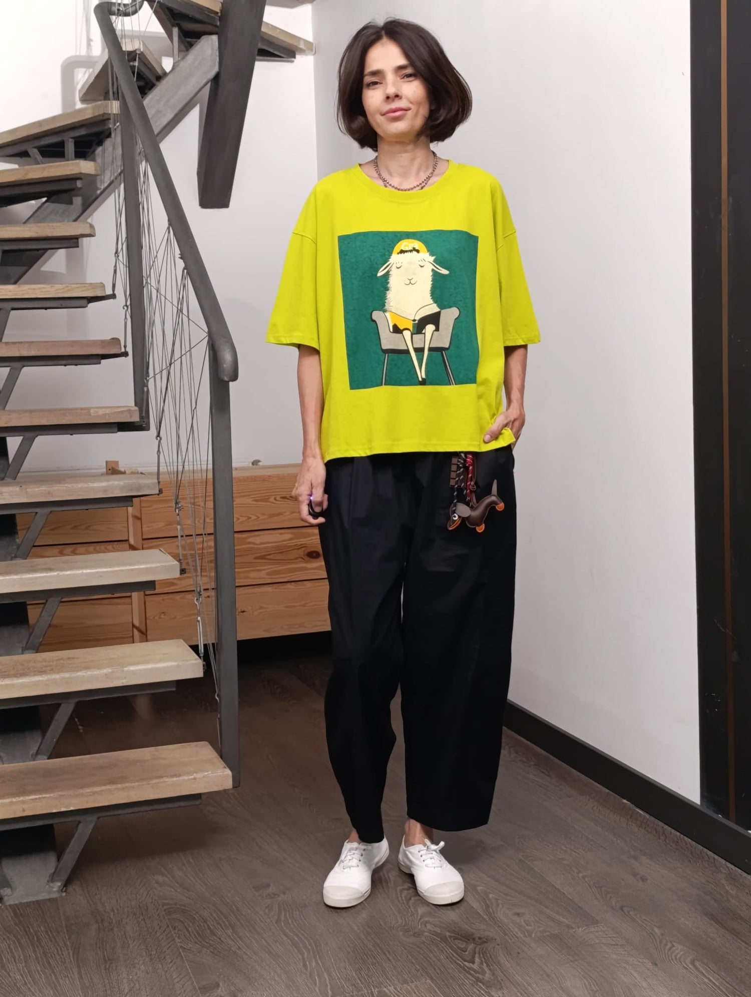 Femeie purtând tricou galben cu imprimeu lămă și pantaloni negri largi, ținută casual