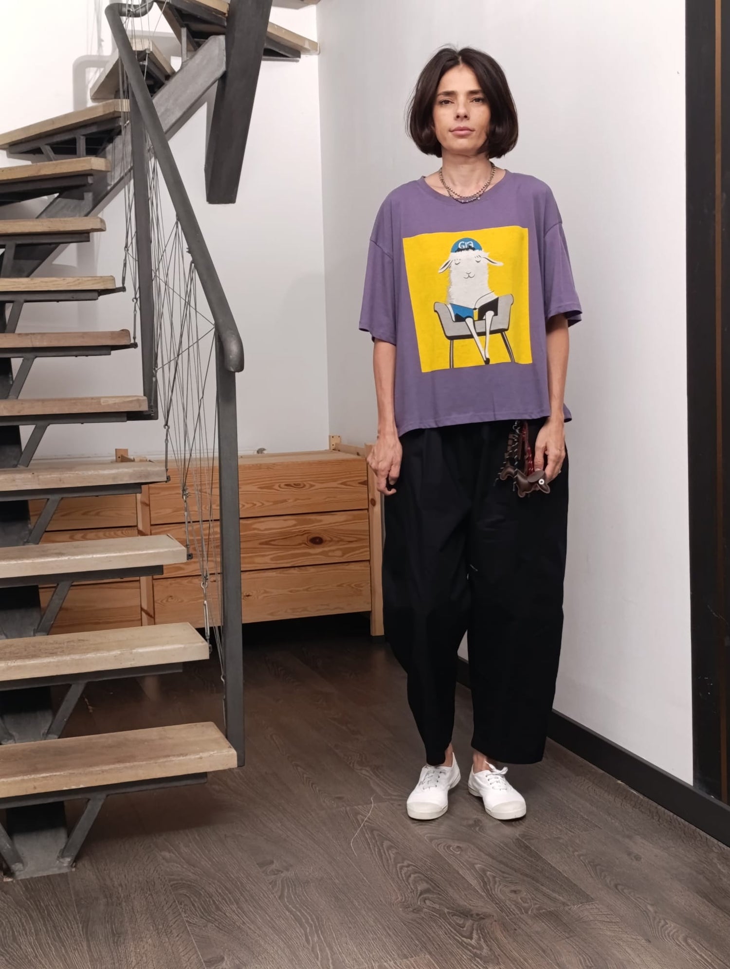  Tricou violet cu imprimeu galben și lămă pe scaun, purtat cu pantaloni negri