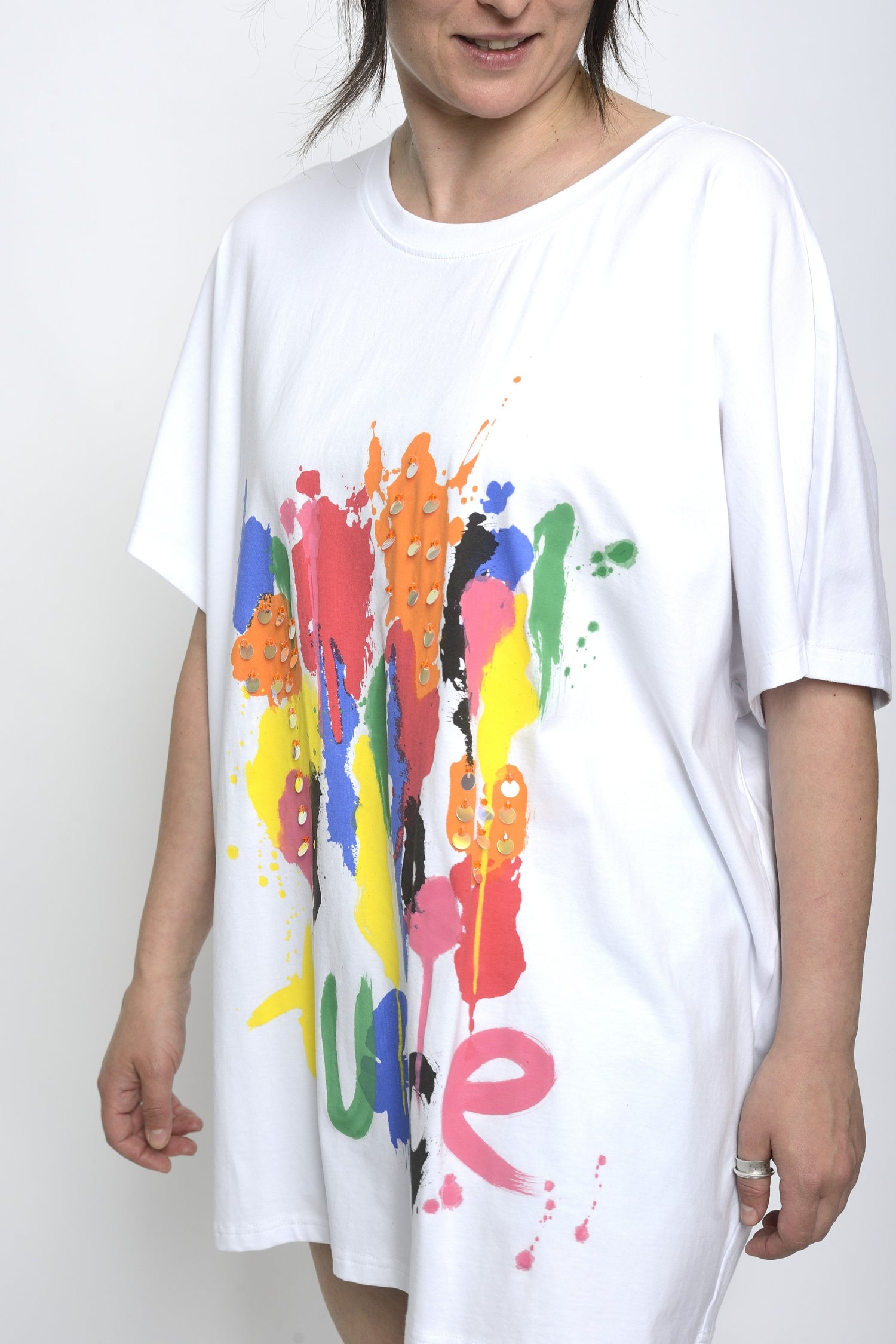 Vedere laterală a unui tricou alb oversized cu imprimeu colorat și paiete
