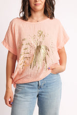 Tricou lejer din bumbac 100%, cu print auriu și design modern cu nod lateral.