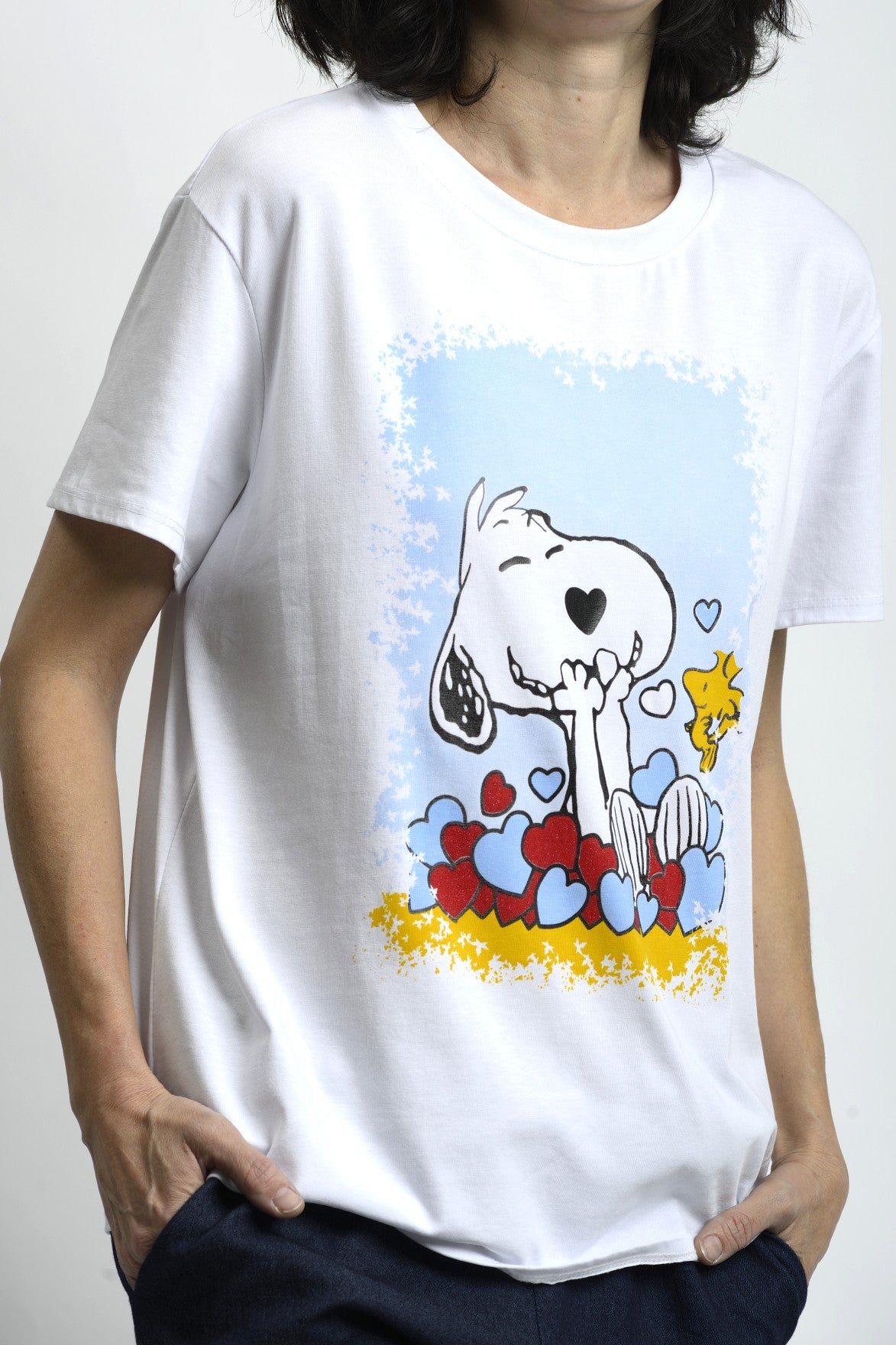 Detaliu imprimeu Snoopy pe tricou alb, grafic jucăuș cu accente de culoare, aspect clar și bine definit.