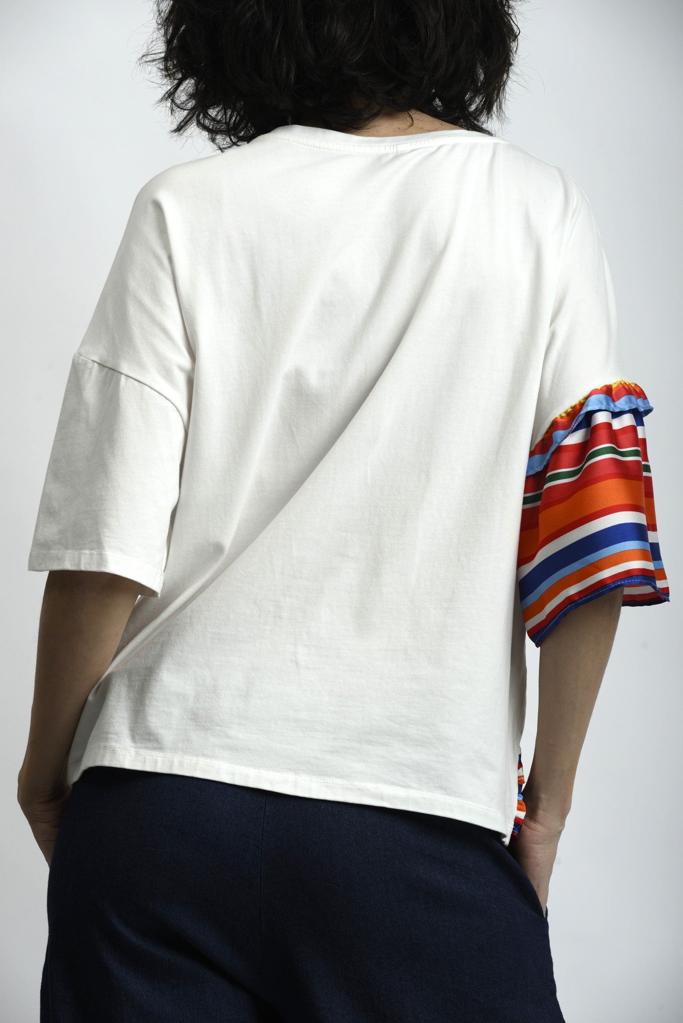 Spatele tricoului alb cu croială dreaptă și finisaj curat.