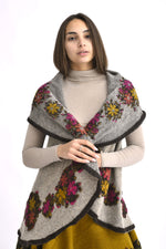 Vestă din lână gri cu flori colorate, purtată pe față, croială tip pelerină cu guler amplu.