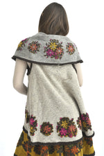 Vedere din spate a vestei gri din lână, cu motive florale pe tiv și pe umeri.