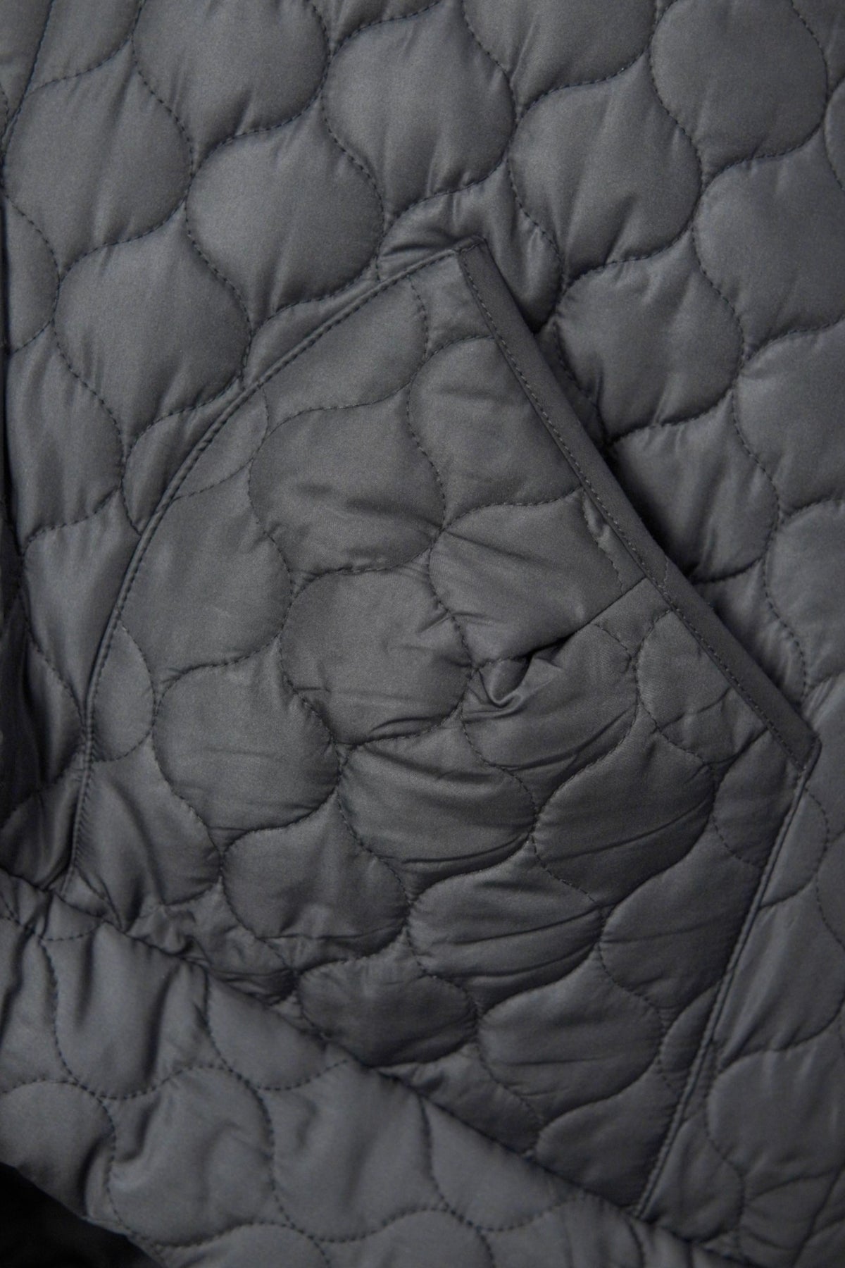  Detaliu buzunar vestă matlasată neagră, evidențiind textura materialului și cusăturile decorative.