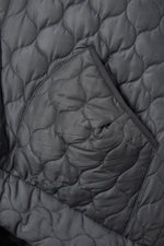  Detaliu buzunar vestă matlasată neagră, evidențiind textura materialului și cusăturile decorative.