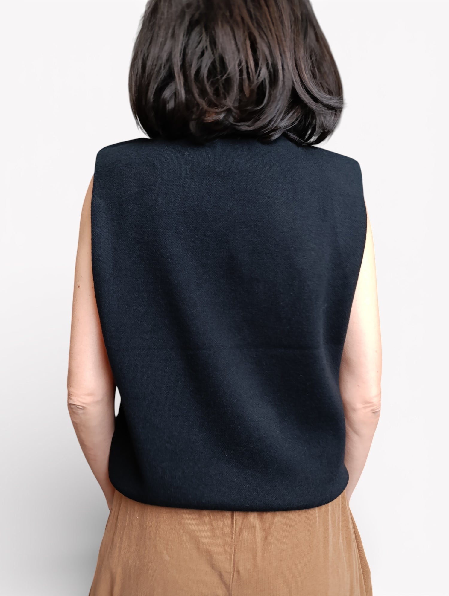 Vestă neagră fără mâneci, vedere din spate, cu croială dreaptă și umeri structurați.