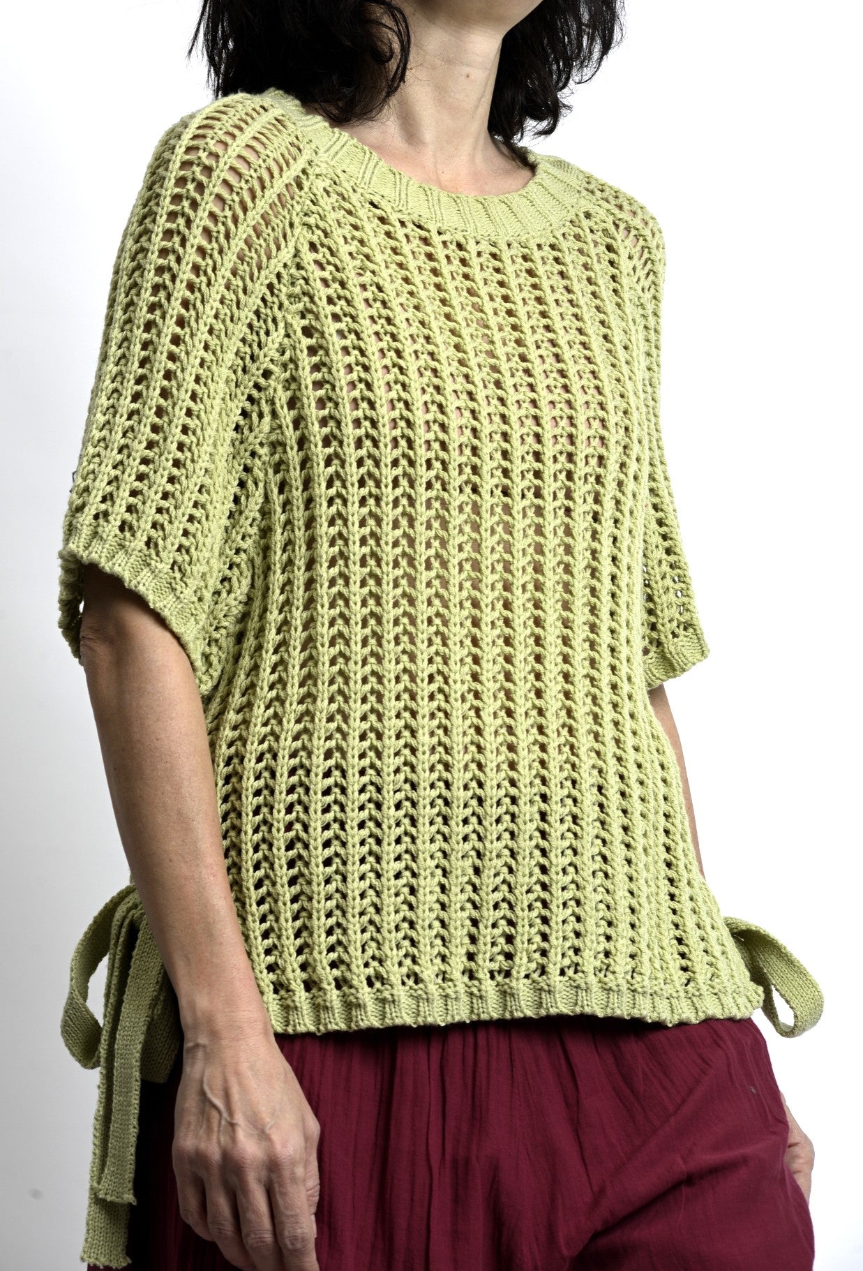 Detaliu tricot aerisit la vestă tip plasă, cu model deschis și cădere lejeră.