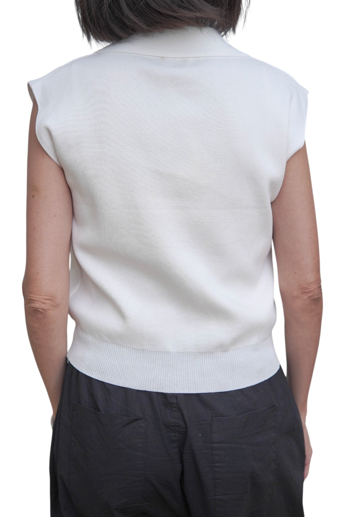 Spatele unei veste polo albe, damă, cu tiv elastic și croială dreaptă.
