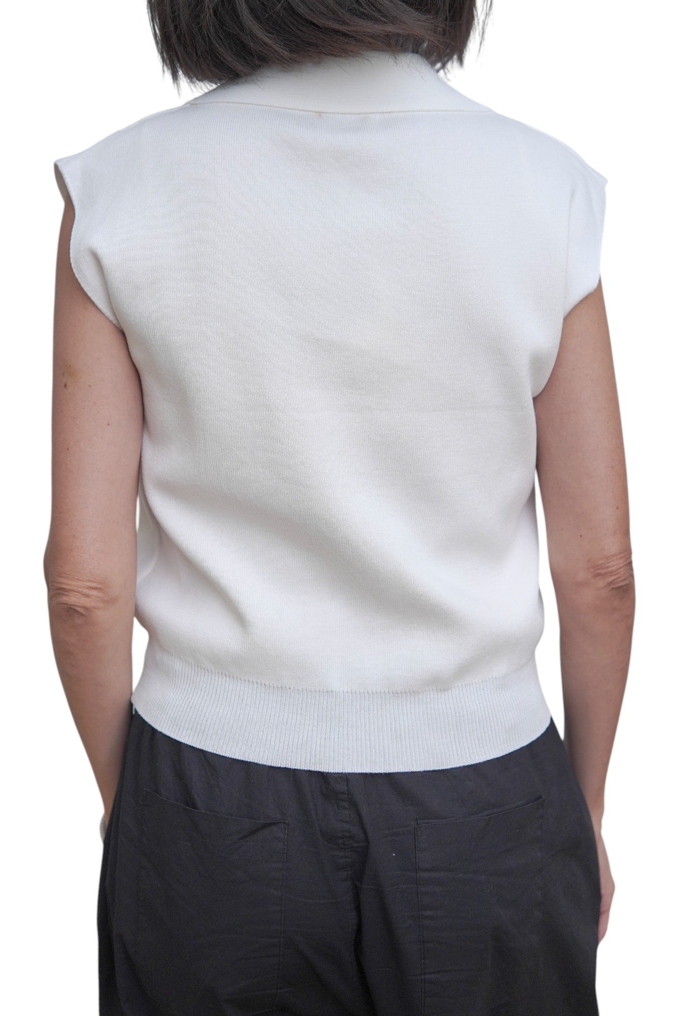 Spatele unei veste polo albe, damă, cu tiv elastic și croială dreaptă.