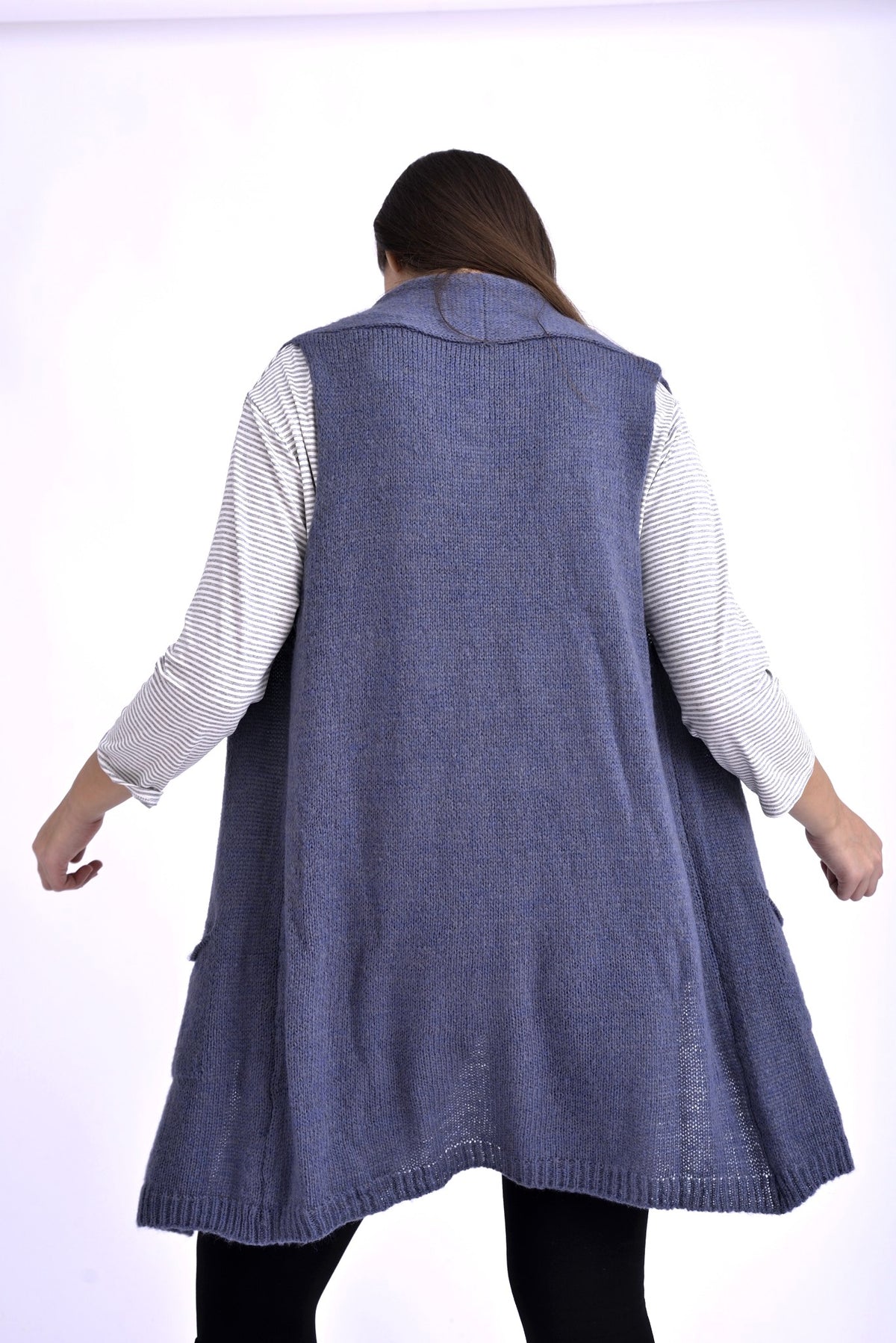 Detaliu frontal al unei veste tricotate bleumarin, cu buzunare și margini finisate, purtată peste o bluză în dungi.