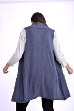 Detaliu frontal al unei veste tricotate bleumarin, cu buzunare și margini finisate, purtată peste o bluză în dungi.