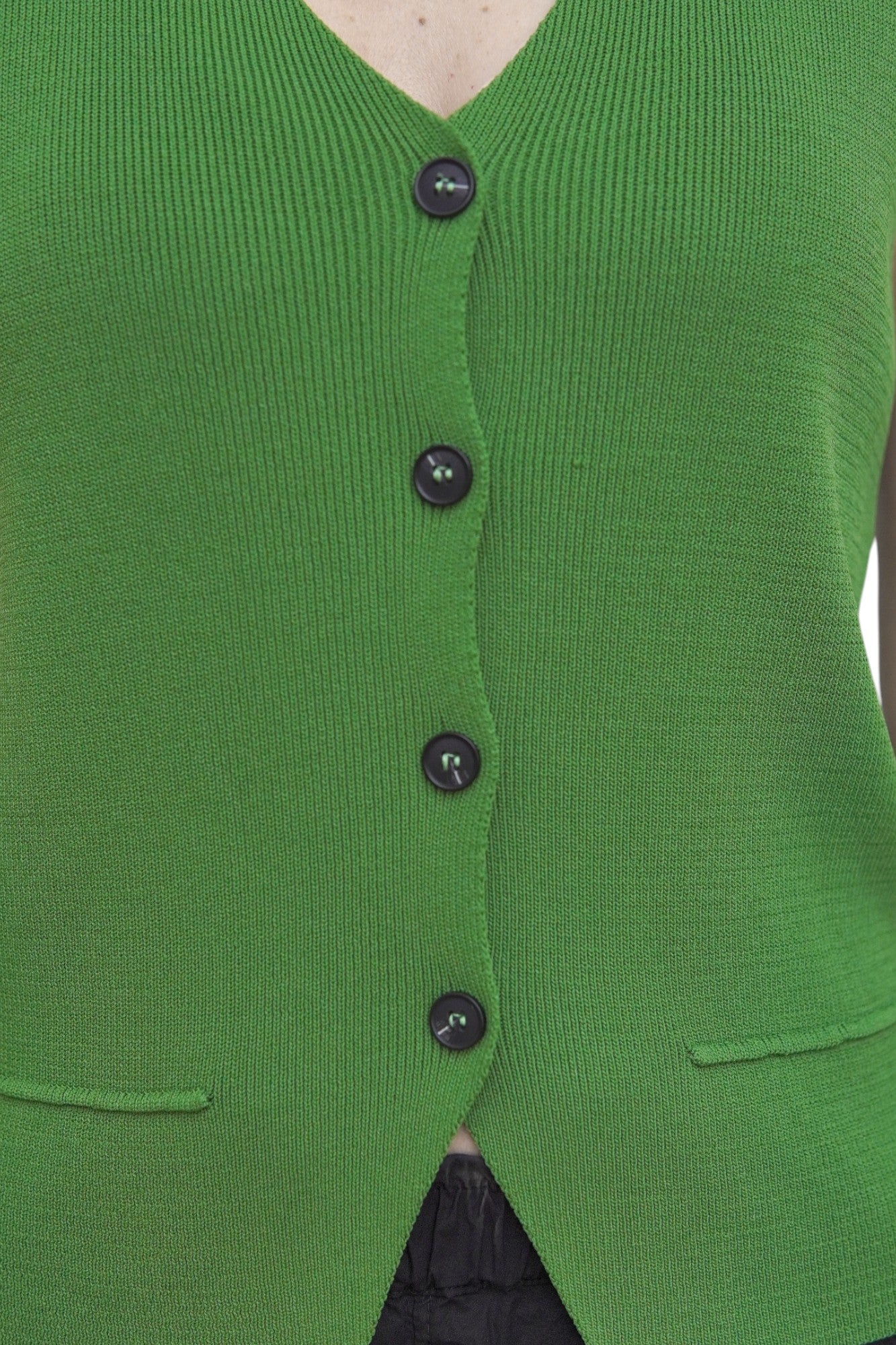 Detaliu textură tricot și nasturi frontali la vesta verde.