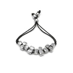 Brățară handmade din aluminiu reciclat cu elemente în formă de cuburi, dispusă pe șnur negru ajustabil – bijuterie eco-friendly minimalistă.
