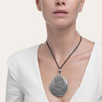 Colier handmade din aluminiu reciclat, purtat de o femeie, cu pandantiv format din trei cercuri argintii de dimensiuni diferite, pe un șnur textil negru – design modern și elegant.