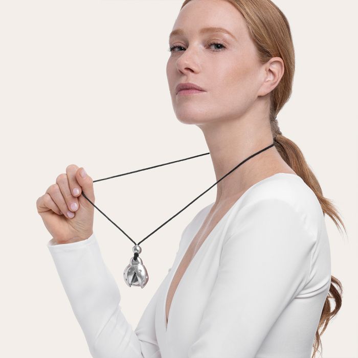Colier handmade din aluminiu reciclat, purtat de o femeie, cu pandantiv în formă de buburuză argintie și șnur textil negru – design modern și ludic.