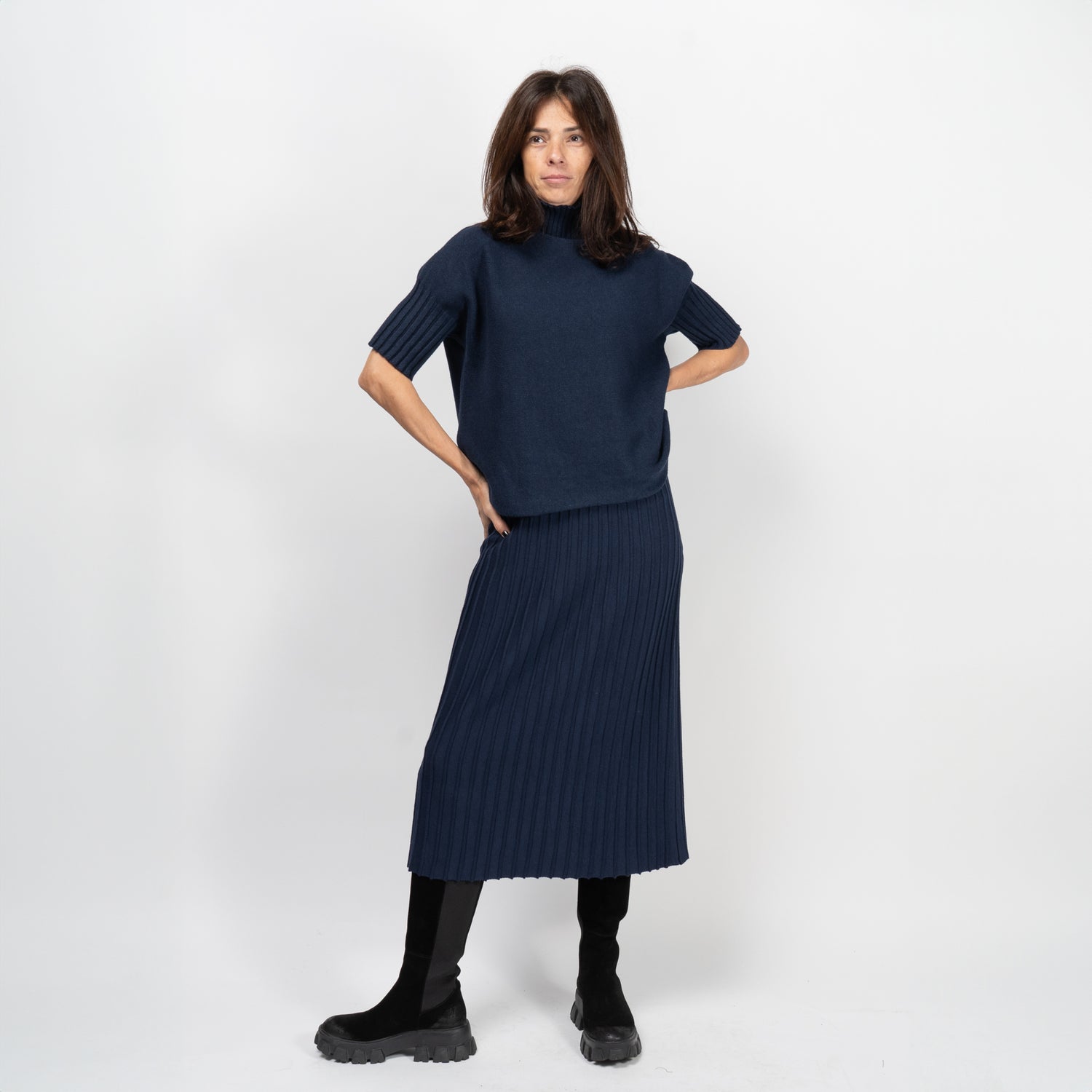 Femeie purtând pulover bleumarin cu pantaloni și bocanci, într-o ținută casual