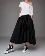 All Above Boutique black cotton asymmetric midi skirt with applied floral details and elastic waist.
