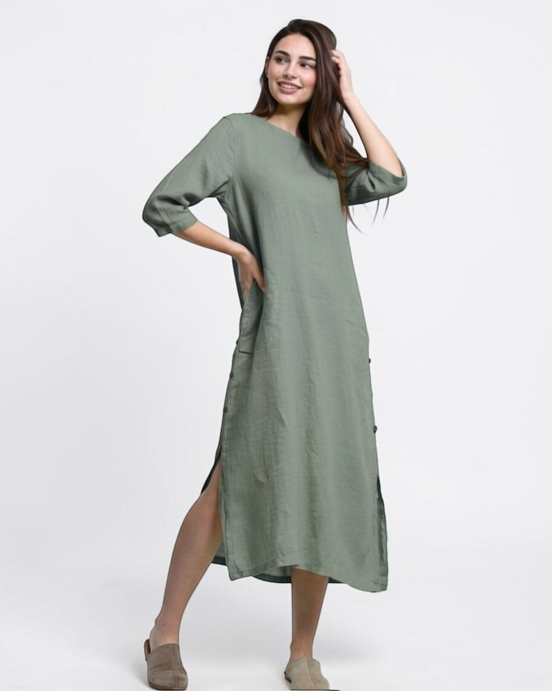 All Above Boutique sage green linen midi dress with 3/4 sleeves, side buttons, and high slits. Model is wearing flats.