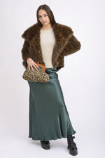 All Above Boutique animal print clutch with wooden frame and gold chain, worn by a model in a faux fur coat and satin skirt.