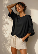 All Above Boutique black cotton 3/4 sleeve relaxed fit blouse with ruffled cuffs, worn by a model.