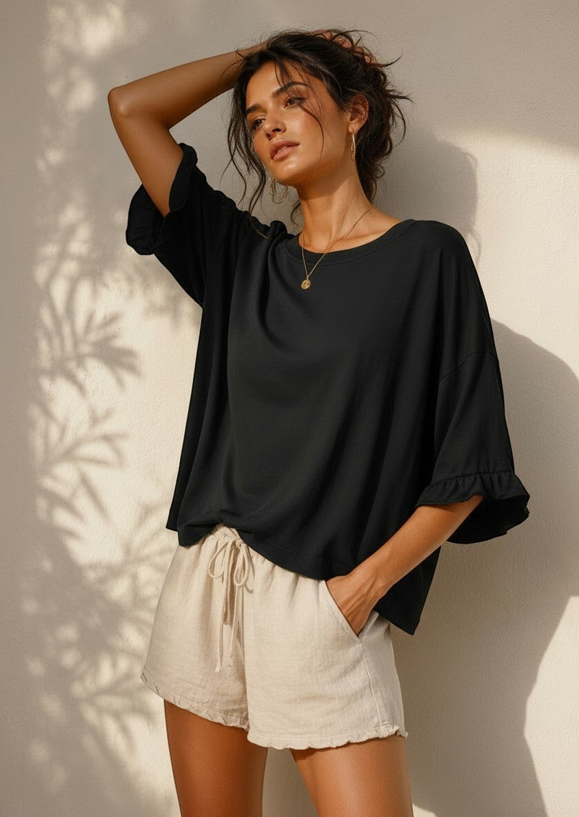All Above Boutique black cotton 3/4 sleeve relaxed fit blouse with ruffled cuffs, worn by a model.