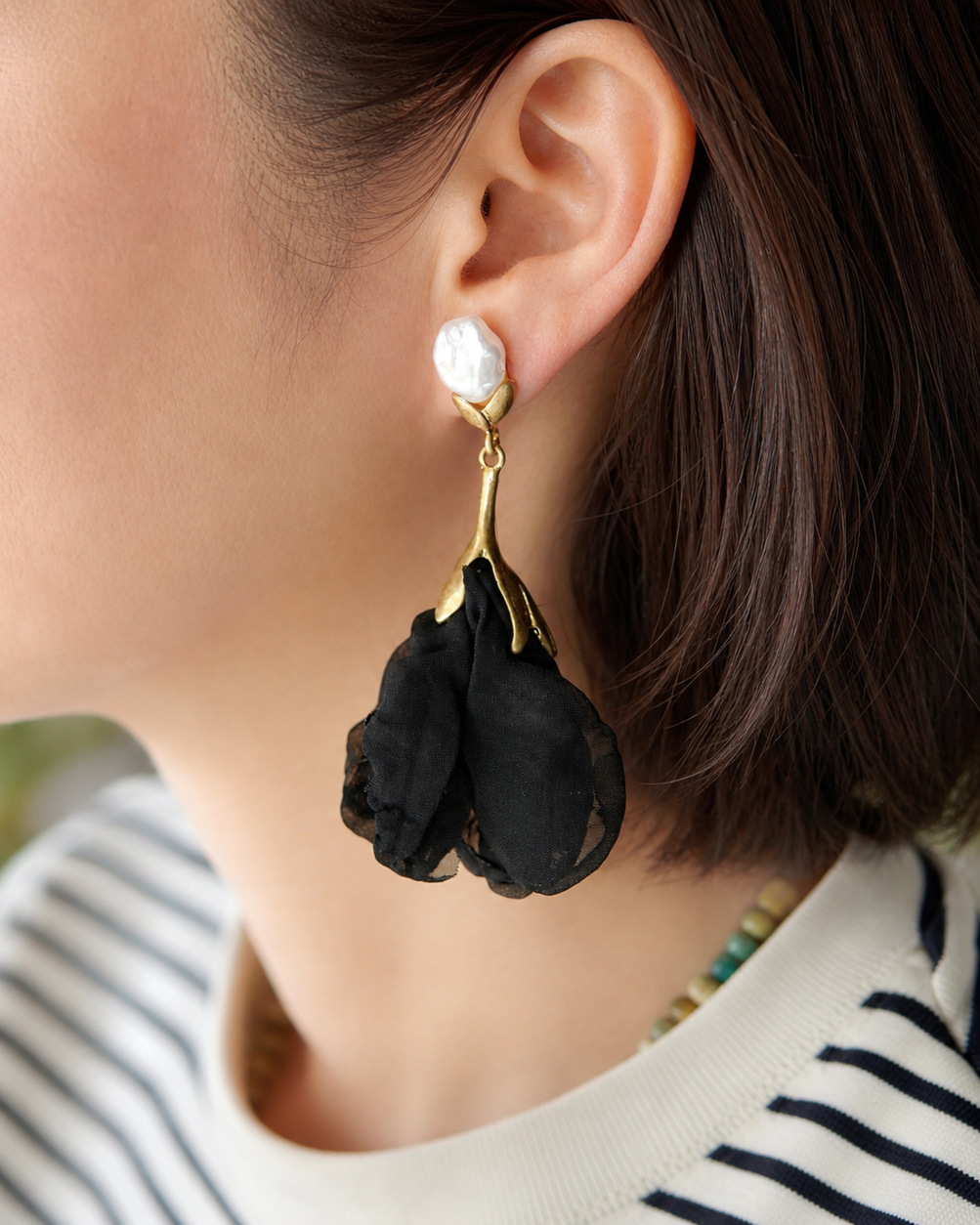 All Above Boutique black satin flower earrings with white pearl and gold-tone metal detail. Dangling floral design.