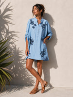 All Above Boutique light blue denim shirt dress with dark blue floral embroidery, roll-tab sleeves, and mandarin collar.