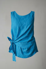 All Above Boutique blue linen sleeveless top with a tie knot detail at the waist and a relaxed fit.