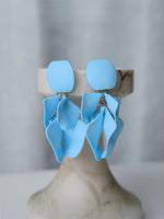 All Above Boutique light blue matte metal petal drop earrings with geometric rhombus base. Elegant statement jewelry.