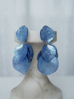 All Above Boutique statement earrings with layered blue iridescent petals, lightweight and feminine design.