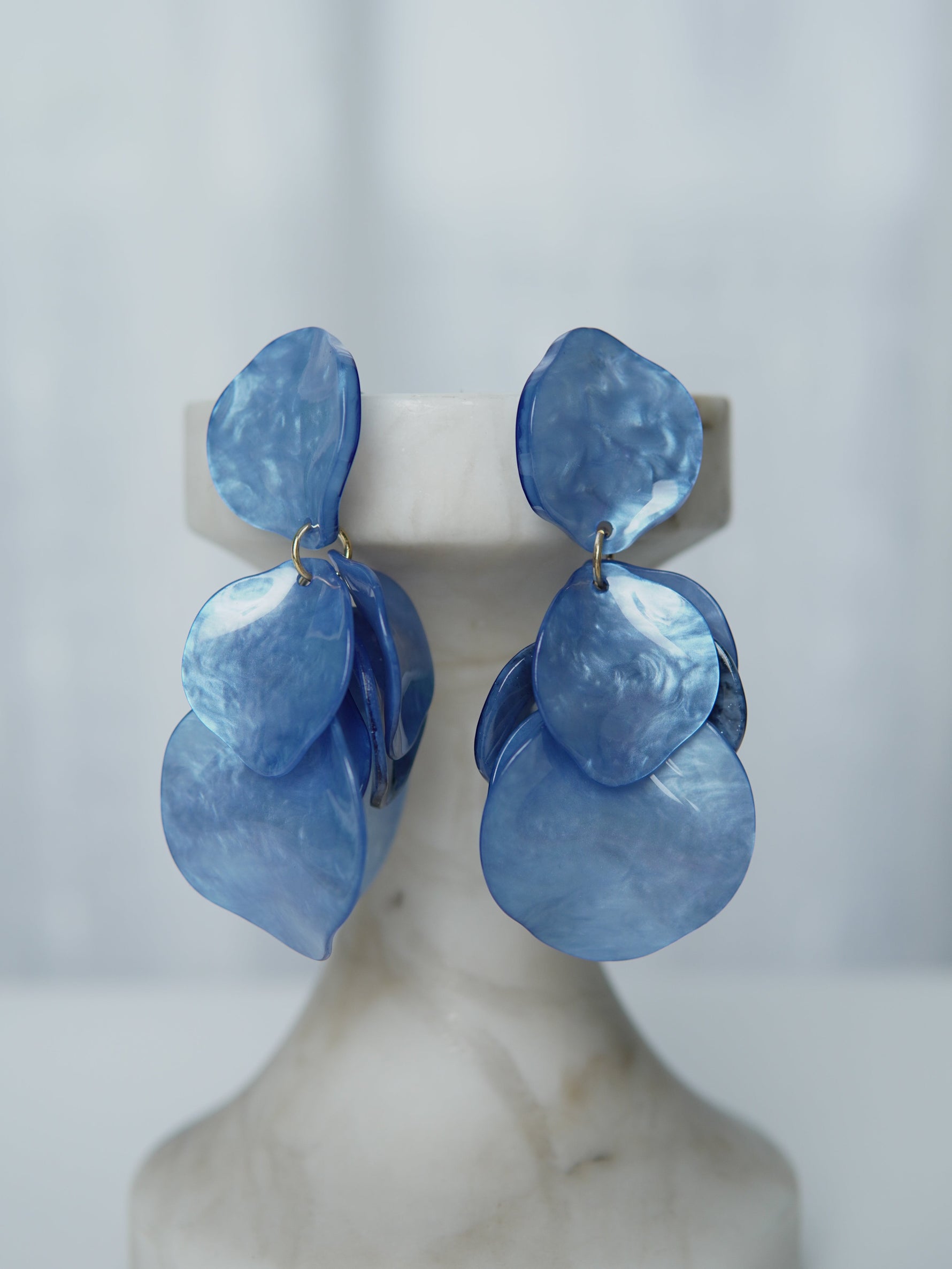 All Above Boutique statement earrings with layered blue iridescent petals, lightweight and feminine design.