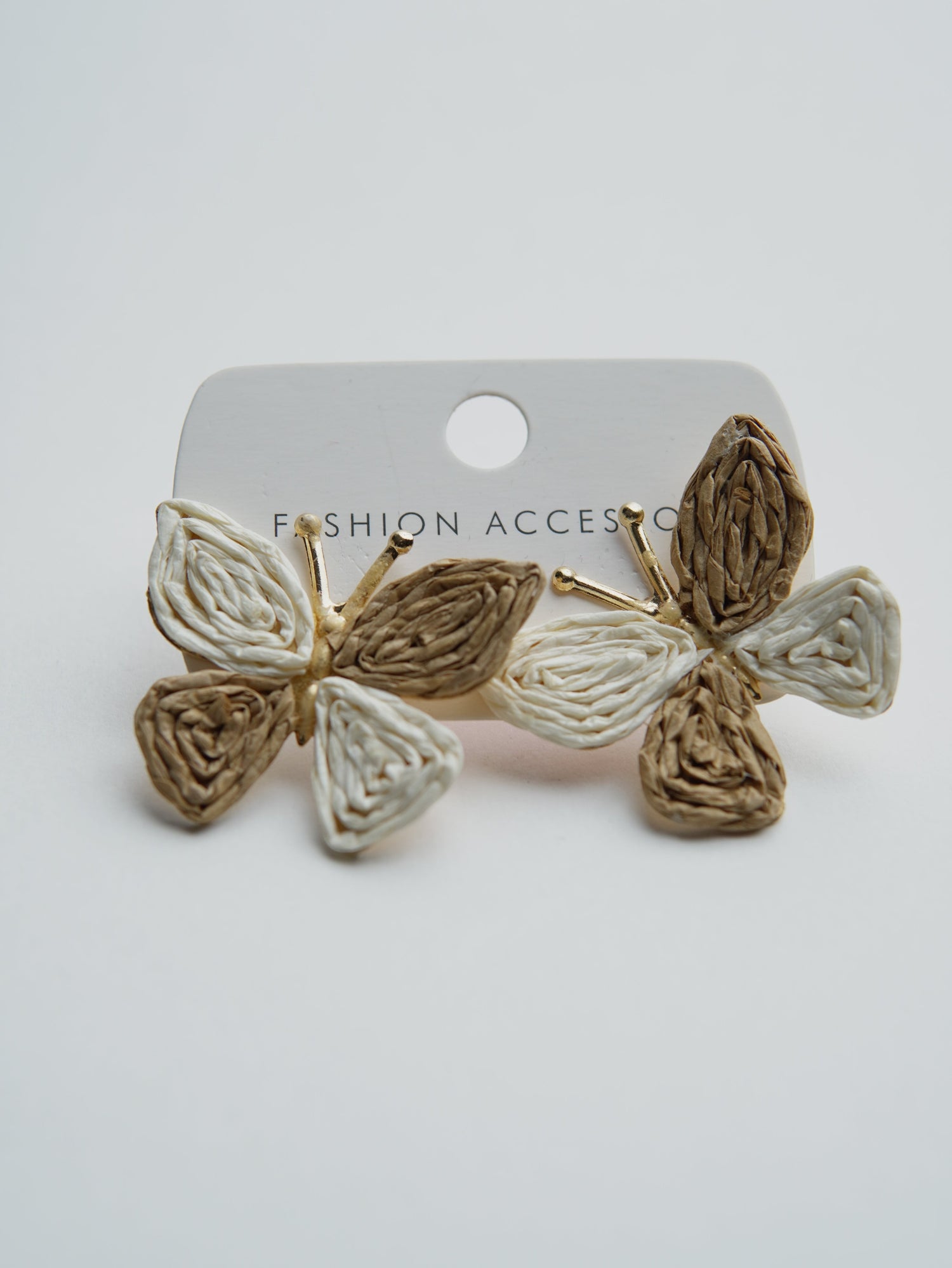 All Above Boutique butterfly earrings made of woven straw in beige and white, perfect for a boho summer look.