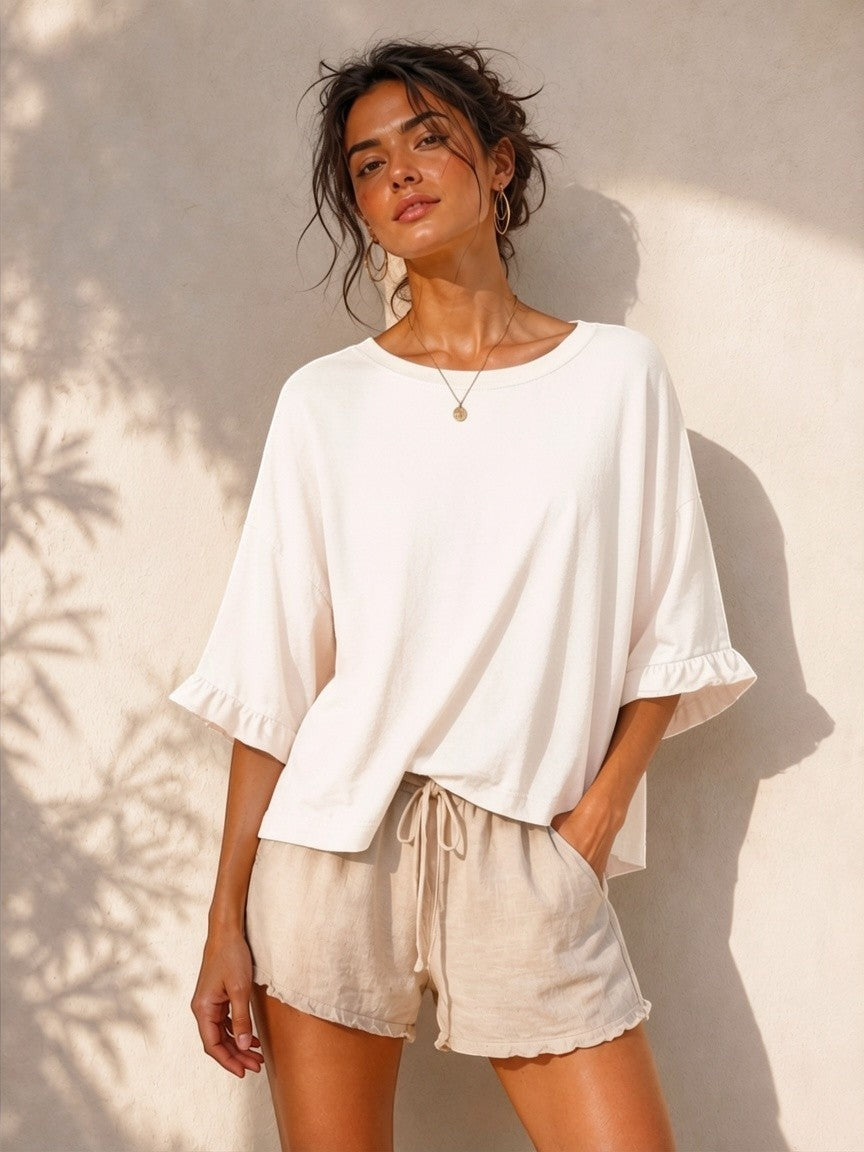 All Above Boutique cream cotton 3/4 sleeve relaxed fit blouse with ruffled cuffs and crew neck.
