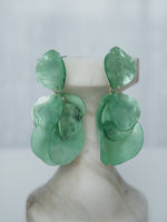 All Above Boutique statement earrings with layered green petals and iridescent finish. Lightweight and versatile.