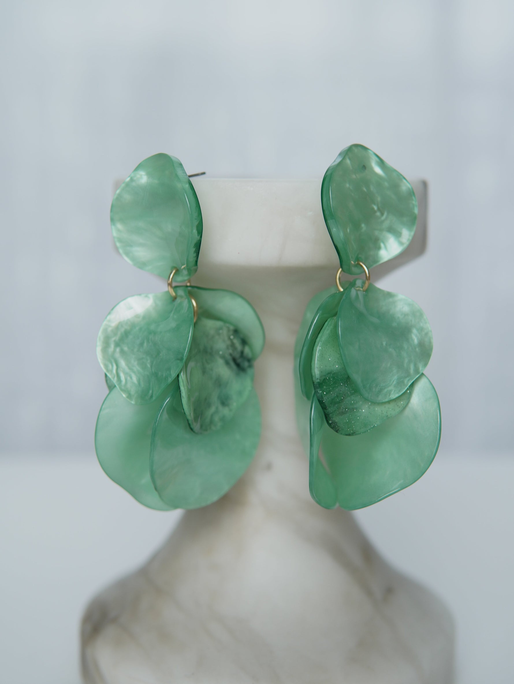 All Above Boutique statement earrings with layered green petals and iridescent finish. Lightweight and versatile.