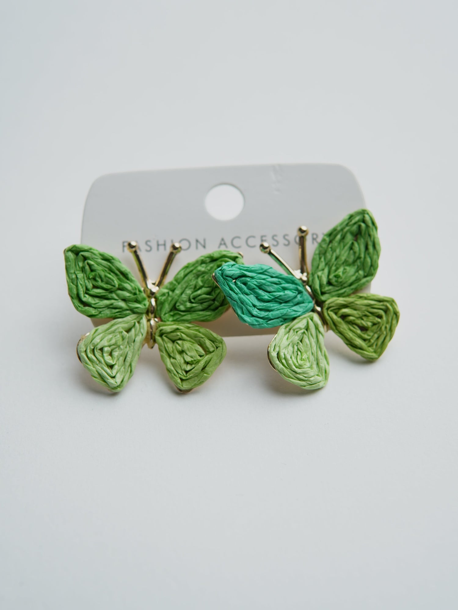 All Above Boutique green woven straw butterfly earrings with gold accents, perfect for a boho summer look.