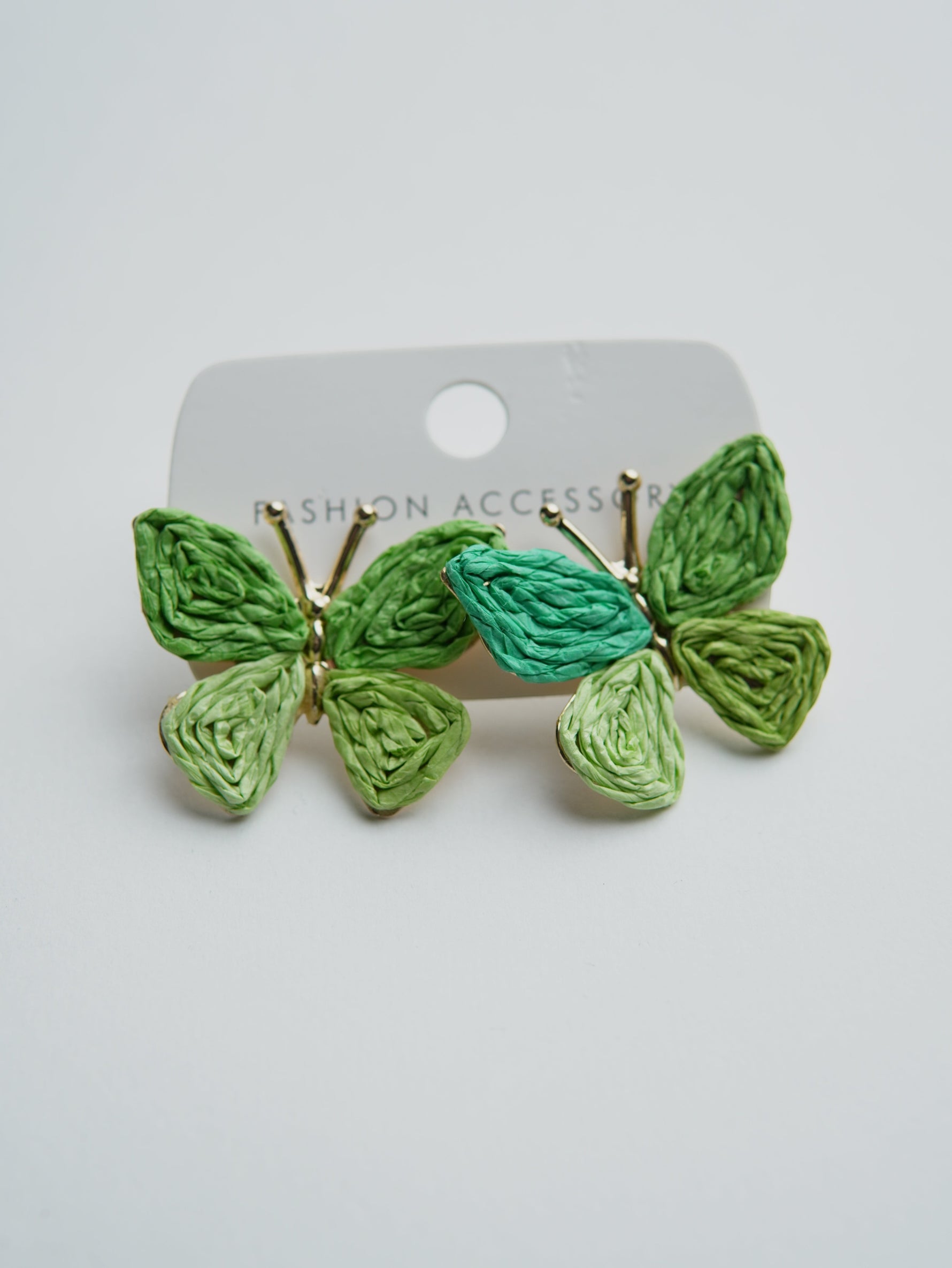 All Above Boutique green woven straw butterfly earrings with gold accents, perfect for a boho summer look.