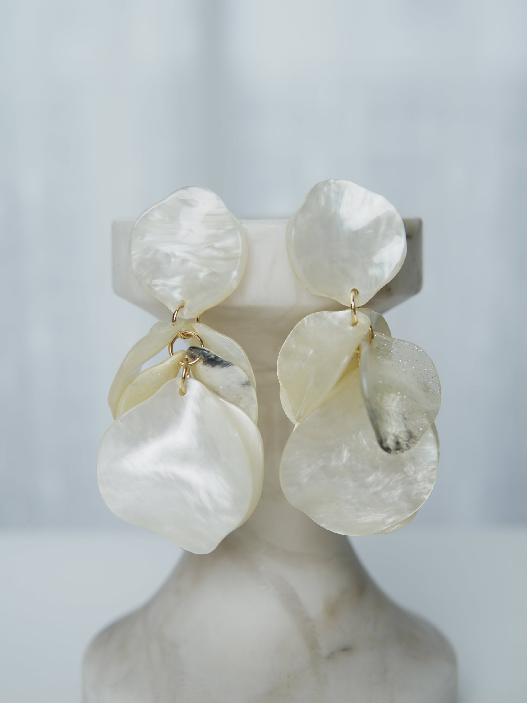 All Above Boutique statement earrings with layered mother-of-pearl petals in iridescent white, dangling design.