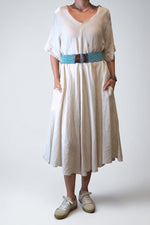 All Above Boutique natural linen V-neck A-line midi dress with side pockets and short sleeves, styled with a turquoise beaded belt.