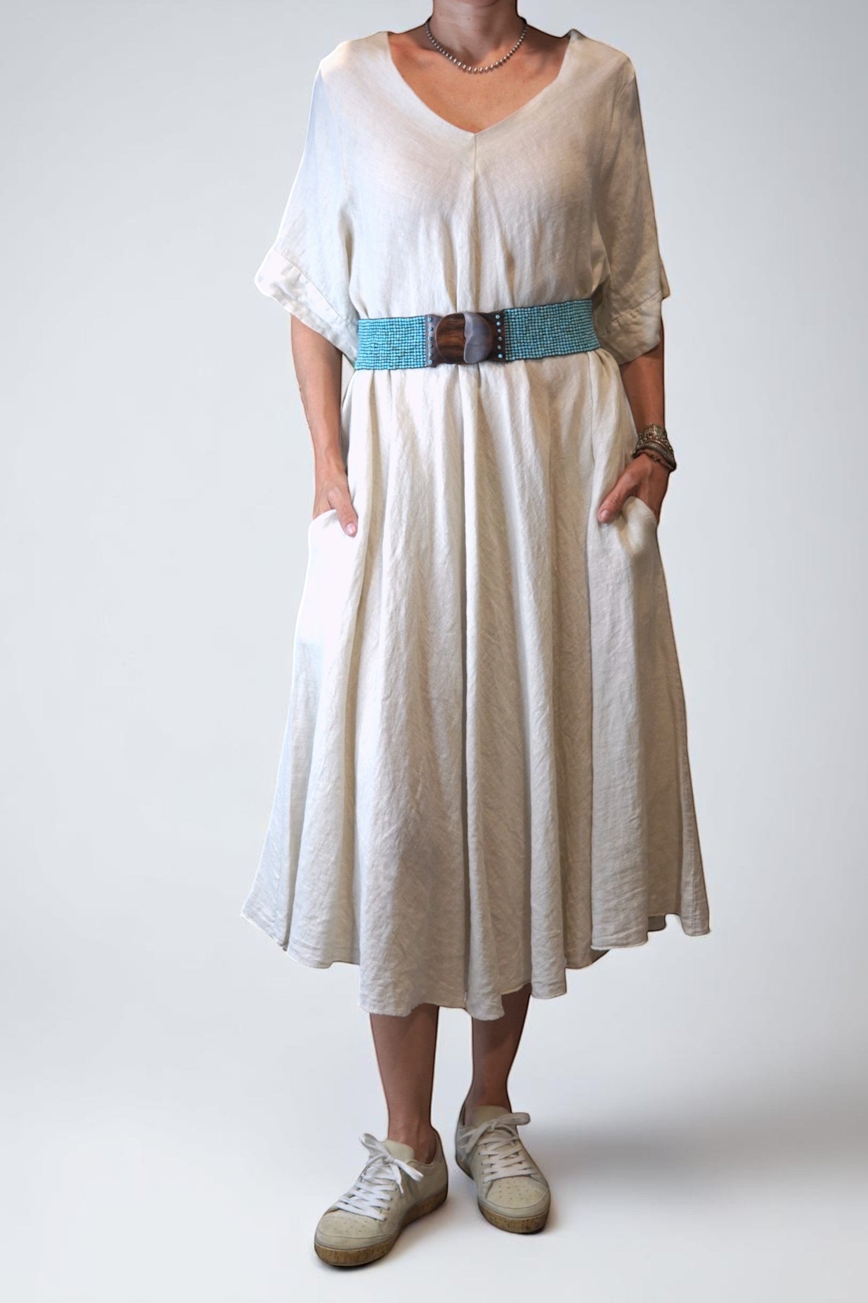 All Above Boutique natural linen V-neck A-line midi dress with side pockets and short sleeves, styled with a turquoise beaded belt.