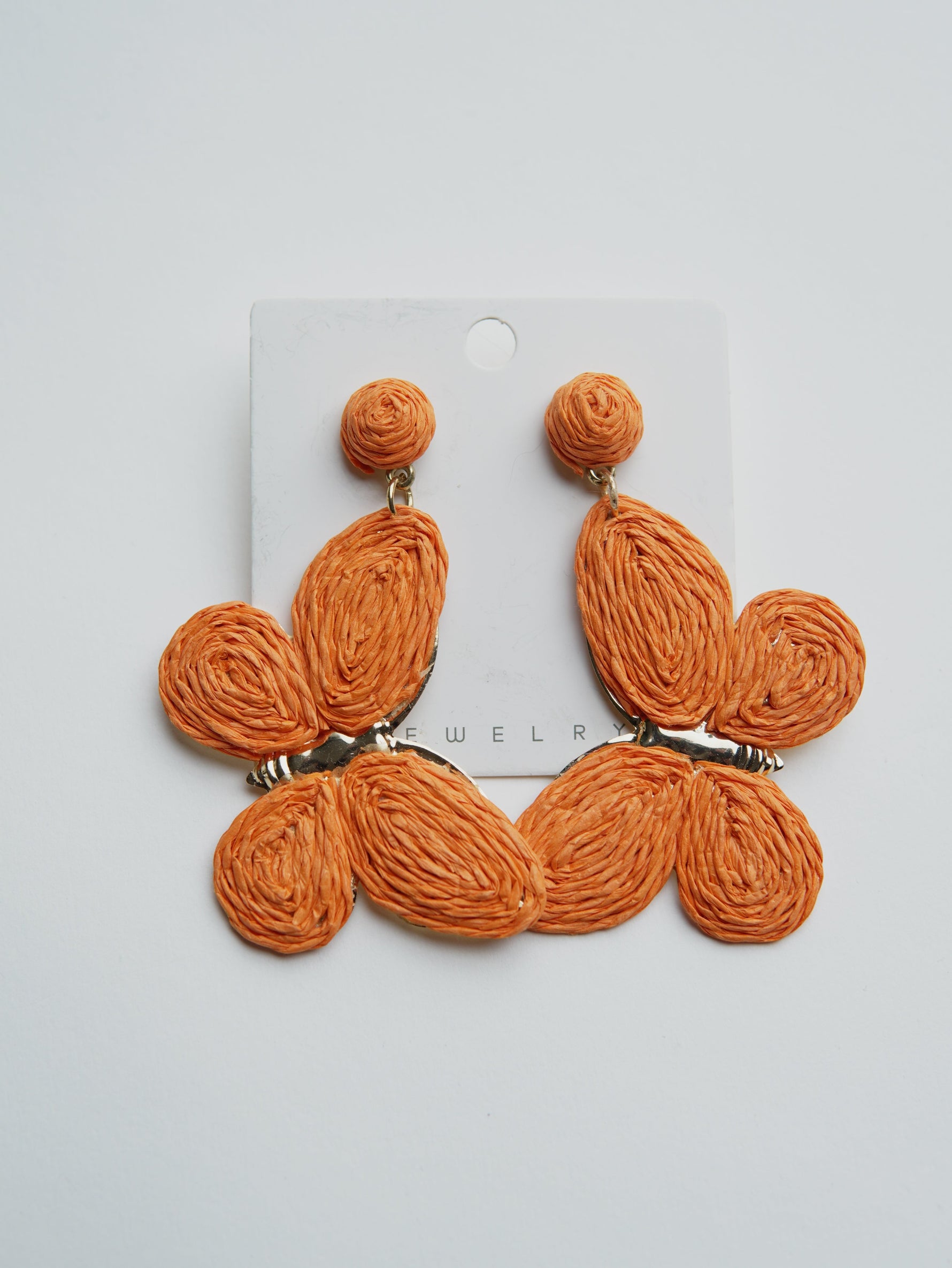 All Above Boutique orange raffia butterfly statement earrings with gold-tone hardware.