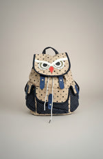 All Above Boutique beige canvas backpack with playful owl face, navy polka dot accents, and adjustable straps.
