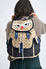 All Above Boutique owl canvas backpack with playful print, drawstring closure, and adjustable straps. Beige with navy polka dots.