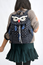 All Above Boutique navy canvas backpack with playful owl face design, white polka dots, and blue accents. Adjustable straps.